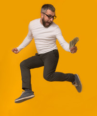 Excited man jumping with money on yellow background