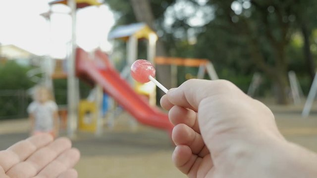 Child abduction or child theft. A stranger with candy in hand on the playground tries to theft a child. Suspicious adult man spies on kids and calls a child to himself. First-person view