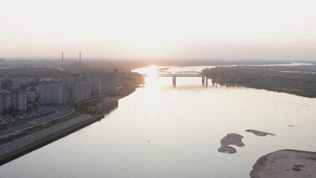 Parasail wing flying on golden sunset horizon landscape. Paraplane flying over river on city bridge architecture background. Paraglider parachute sport aerial view