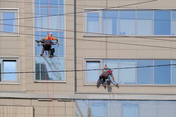 Two industrial climbers wash the windows on the facade of the office building.