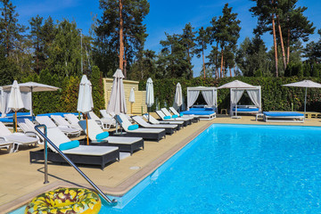 pool with clear water and sunbeds with bungalows near the hotel.