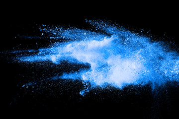 Blue color powder explosion cloud on black background.Closeup of Blue dust particles exhale on dark...