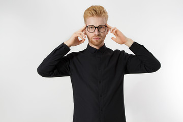 Young man in thinking process. Close up redheaded guy with red beard in black shirt, glasses focus...