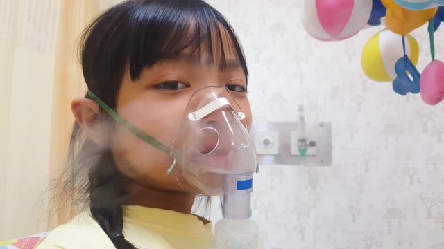 Asian child girl is spraying a medicine to reduce nasal congestion due to bronchitis for treating respiratory diseases