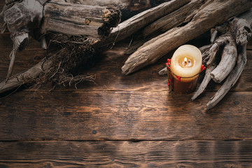 Old dried wood branches and burning candle on brown wooden board background with copy space.