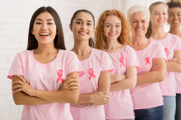 Women In Breast Cancer T-Shirts Standing Next To White Wall