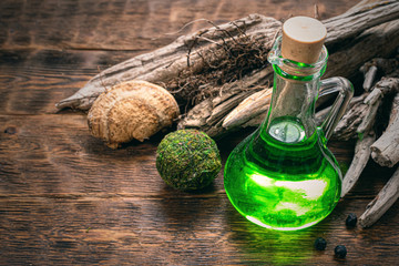 Green magic potion bottle on a wizard table. Herbal medicine with dried ingredients on the table...