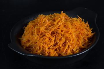 Spicy Korean carrot salad in black plate on black background