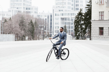 Afro businessman going to office on bike, riding in city