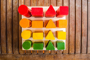Set of blocks of wood of sequences of geometric shapes painted with natural dyes, seen from above, to help the motor development of children.