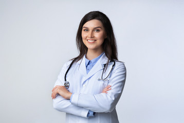 Cheerful doctor standing crossing hands in studio