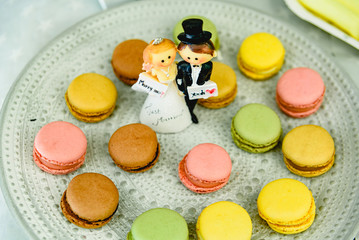 Happy newlywed dolls on a plate with macarons in the candy bar of a wedding.