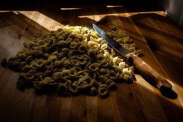 Orecchiette, Italian wheat semolina pasta, on a table and a knife.