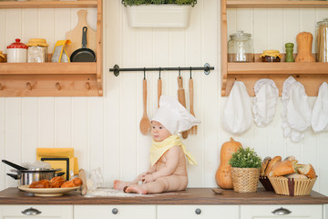 little plus size fatty baker child in chef hat at kitchen table alone