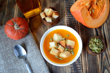 Pumpkin soup with croutons and seeds in a bowl on a wooden table