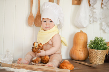 little baker child in chef hat at kitchen table alone