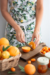 Obraz na płótnie Canvas Person with printed kitchen apron cutting an orange