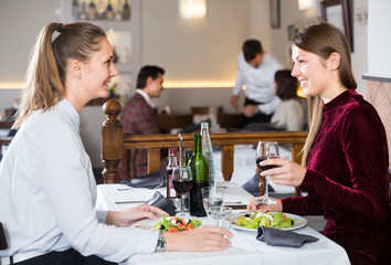 Two happy girls nicely spending time together, enjoying dinner in restaurant