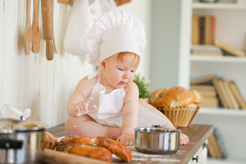 little baker child in chef hat at kitchen table alone