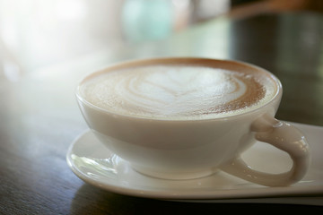 cappuccino coffee cup with beautiful latte art on old dark wooden table in coffee shop.