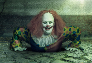 a grin killer clown rising from the sewer