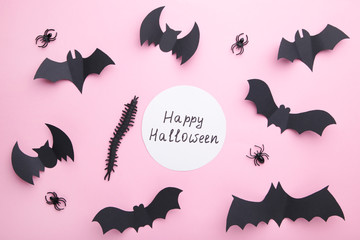 Inscription halloween with paper bats with spiders on pastel pink background. Halloween concept
