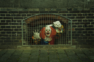 scary clown with a knife caged behind a lattice