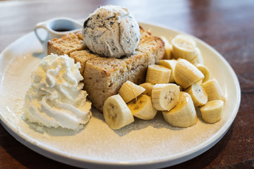 Close Up on, Honey Toast, Bread Buttered Toast, Banana, Ice Cream and Whipped Cream Dessert on a white Dish