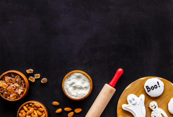 spooky halloween figures with rolling pin, flour, sugar, almond for cooking treat on black background top view mock up