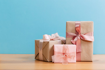 set of beautiful different gift boxes made by handmade with pink bows on a wooden table with a blue background. flat lay