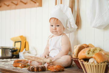 little baker child in chef hat at kitchen table alone