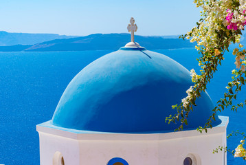 Beautiful view of white typical village and Aegean Sea i. View of blue domed churches -famous tourist attraction in Greece.