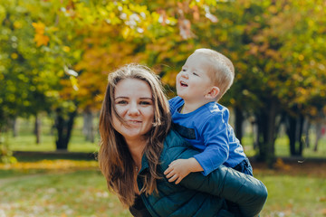 portrait of a beautiful young mother with her son walks in the autumn park.