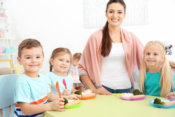 Cute little children eating lunch in kindergarten