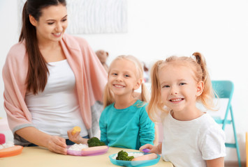 Obraz na płótnie Canvas Cute little children eating lunch in kindergarten