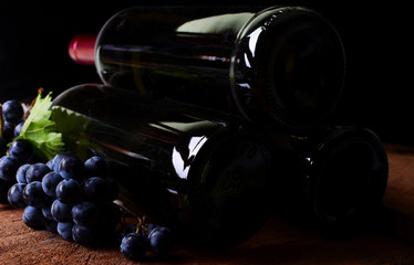 Obraz premium Wine bottles and grapes on a black background