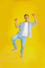 Fototapeta na wymiar Happy attractive man dancing on yellow background