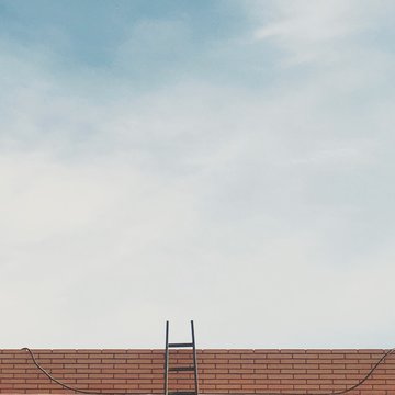 A ladder leans against a red tile roof.