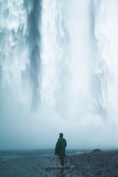 a man is stading by a large waterfall