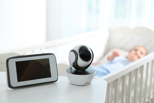 Baby Monitor And Camera On Table Near Crib With Child In Room. Video Nanny