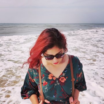 A  red haired girl is standing at the beach