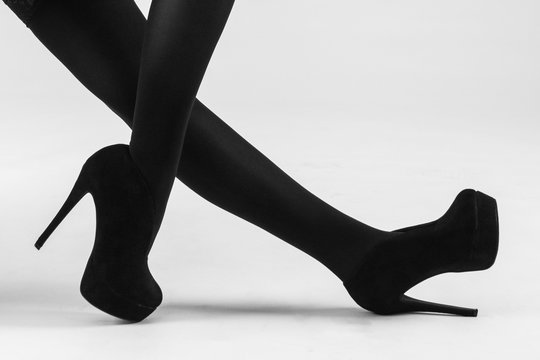 A woman's legs wearing black stockings and black stilletos.