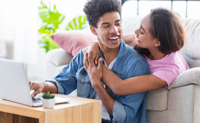 Obraz premium Girlfriend embracing her boyfriend while they working on laptop together