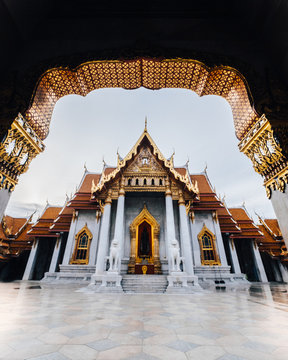 An ornate building with gold molding, white columns and statues