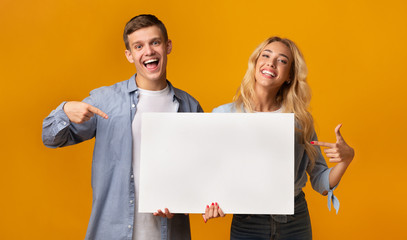 Young people holding blank advertising board and pointing on it