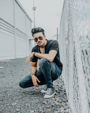 Man crouching next to chainlink fence
