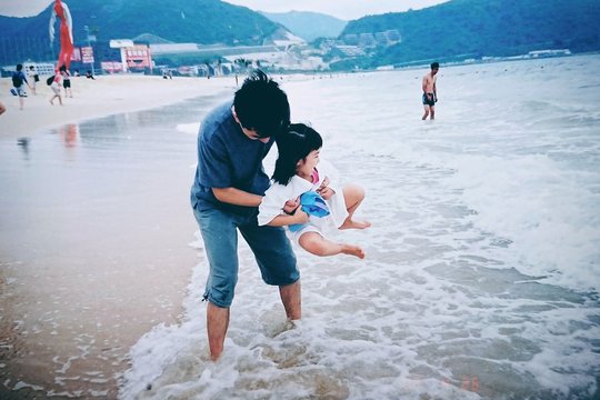 Father playing with little daughter in sea surf