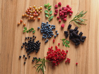 summer berries on a wooden table with greens