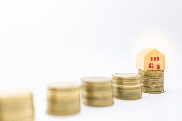 Money, Home Loan, Business and Finance concept. Close up of wooden house toy on top of stack of golc coins on white background and copy space.