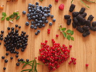 summer berries on a wooden table with greens